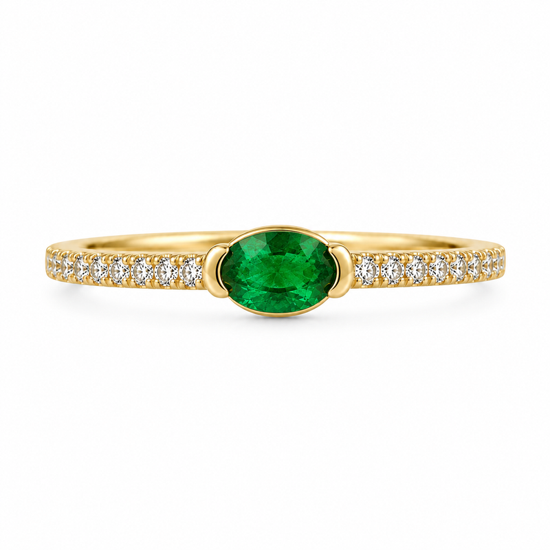 A modern spin on a classic design, this chic ring showcases a vibrant genuine oval emerald set horizontally in a sleek half-bezel East-West setting. Crafted in warm 14K yellow gold and framed by a sparkling diamond-accented band, it features 1/3 CTW of emerald brilliance paired with 1/6 CTW of diamonds for an unforgettable pop of green elegance.