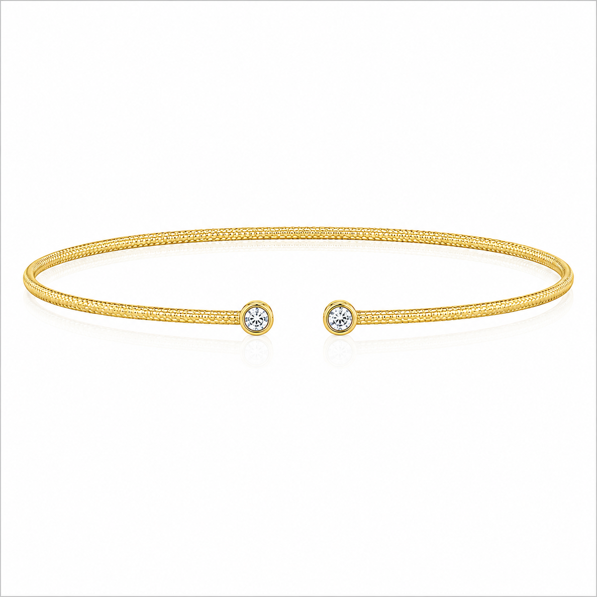 Two bezel-set round diamonds accent the open ends of a slender 14K yellow gold bangle. The diamonds total 1/10 carat total weight, while the textured finish adds subtle dimension to the design.